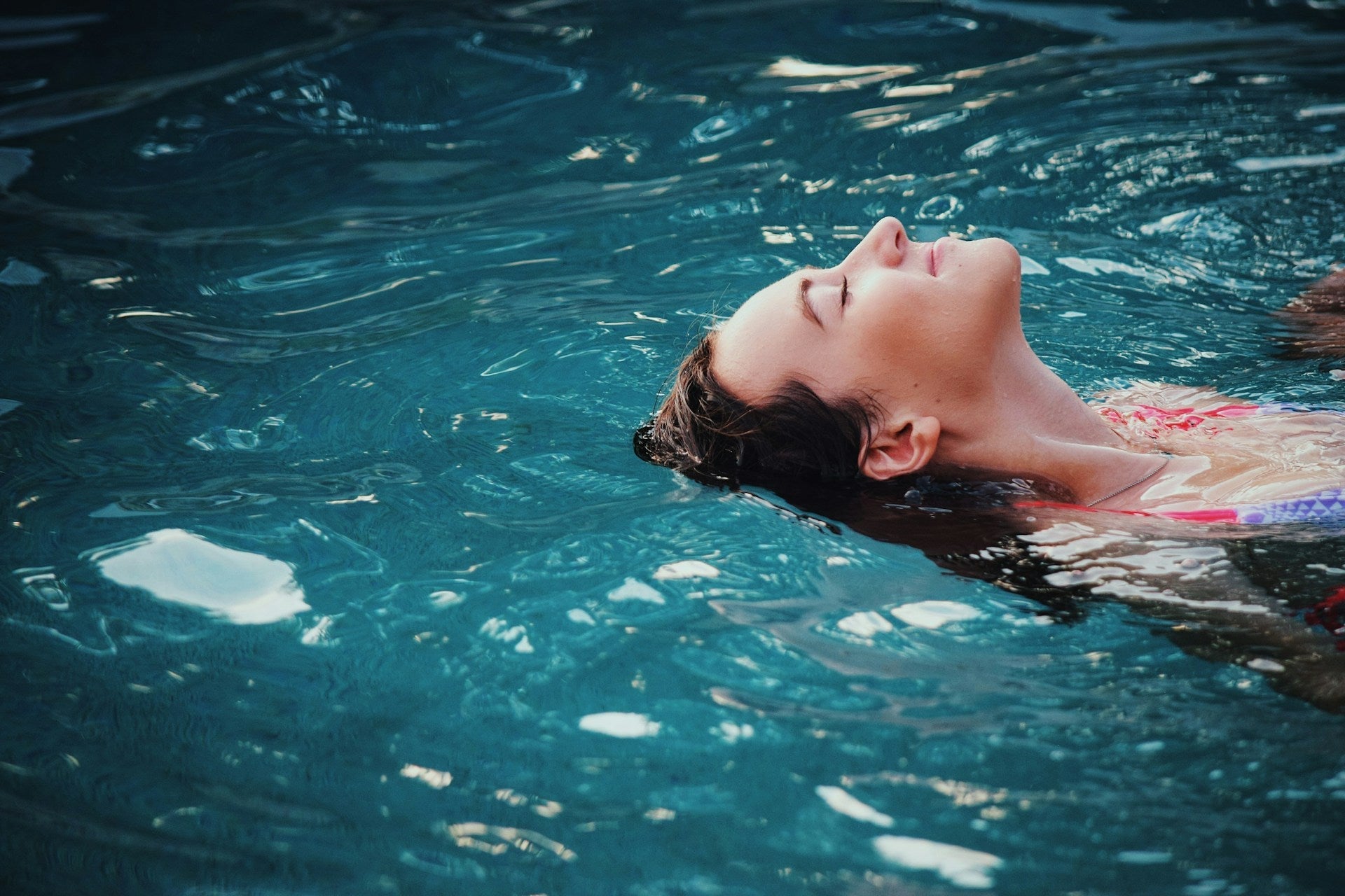 Woman relaxing in the water, representing hair care tips for maintaining healthy hair during water sports activities.